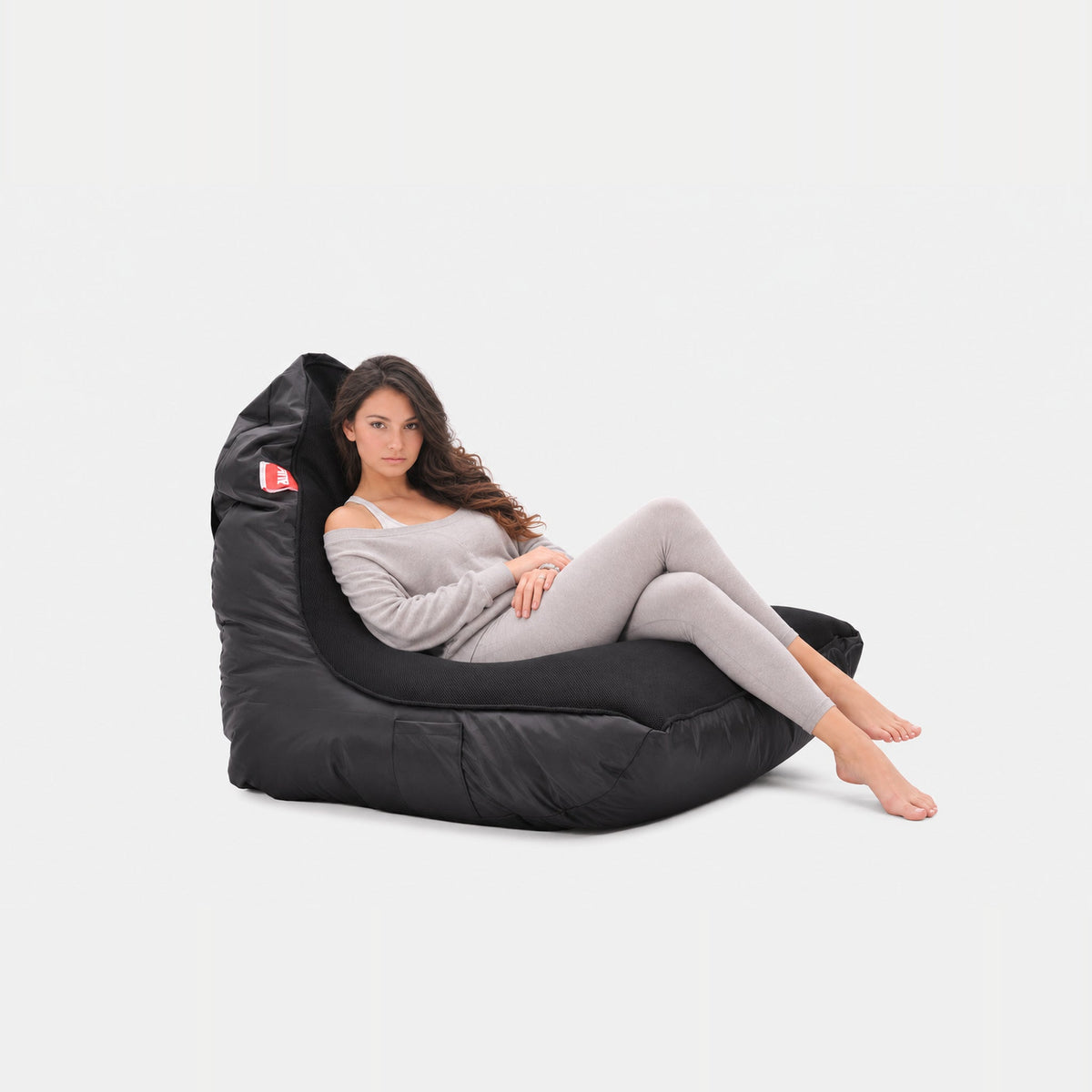 Woman relaxing on the Blackout VIP black beanbag sofa with air-mesh seating